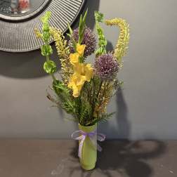 Yellow flowers and purple allium in a green vase with a ribbon