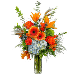 Orange and blue mixed bouquet in a clear glass vase