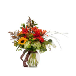 Bouquet of orange lilies and sunflowers in a clear glass vase