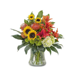Bouquet of sunflowers, orange lilies, and white hydrangea in a glass vase