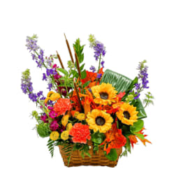 Basket arrangement with sunflowers, carnations, and purple spikes