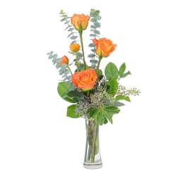 Orange roses in a clear glass vase with eucalyptus