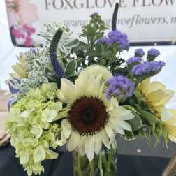 Sunflower and hydrangea bouquet in a glass vase with purple accents