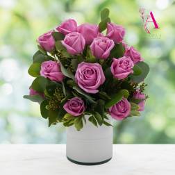 Pink roses arranged in a white vase with green foliage