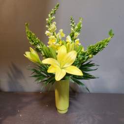 Yellow lilies and snapdragons arranged in a tall vase