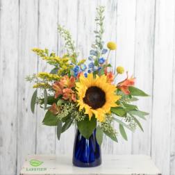 Sunflower bouquet in a blue glass vase with yellow and orange accents