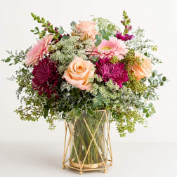 Pink and peach flowers in a glass vase with a gold stand
