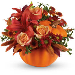 Autumn floral arrangement in a pumpkin container with red lilies and roses