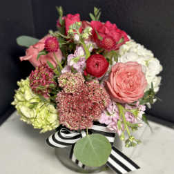 Mixed pink and white bouquet in a glass vase with a striped ribbon