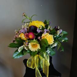 Mixed bouquet with yellow roses, daisies, and a yellow ribbon in a vase