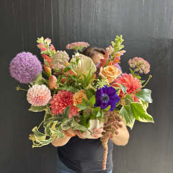Large mixed bouquet with dahlias, roses, and purple allium in a white vase