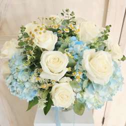 Bouquet of white roses and blue hydrangeas in a clear vase
