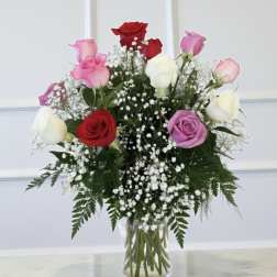 Bouquet of red, pink, purple, and white roses in a clear glass vase