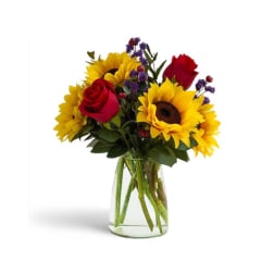 Bouquet of sunflowers and red roses in a clear glass vase