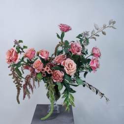 Pink roses arranged in a clear glass vase with trailing greenery