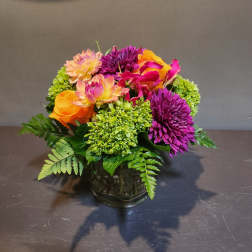 Colorful mixed bouquet in a glass vase with purple, orange, and pink blooms