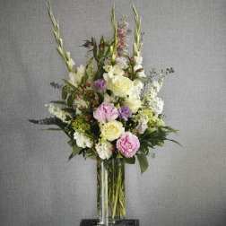 Tall floral arrangement in a clear glass vase with pink, white, and lavender blooms