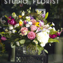 Mixed bouquet of pink roses, lilies, and white hydrangea in a glass vase