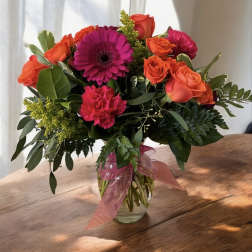 Bouquet of orange and pink flowers in a glass vase with a ribbon