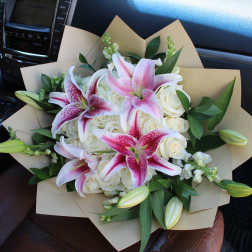 Bouquet of pink lilies and white roses wrapped in tan paper