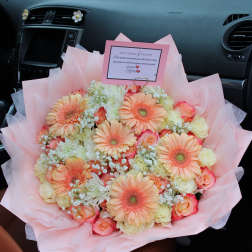 Pink bouquet with peach gerbera daisies and roses in a car seat