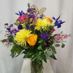 Mixed bouquet in a glass vase with yellow, purple, pink, and orange flowers