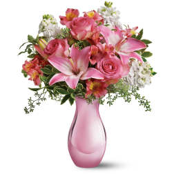 Pink lilies and roses arranged in a pink glass vase