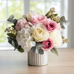 Pink and white roses arranged in a ribbed metal vase