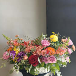 Colorful mixed flower arrangement in a white container on a pedestal