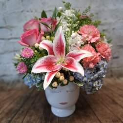 Mixed bouquet with pink roses, lilies, hydrangeas, and carnations in a white vase