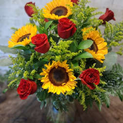 Bouquet of red roses and yellow sunflowers in a glass vase