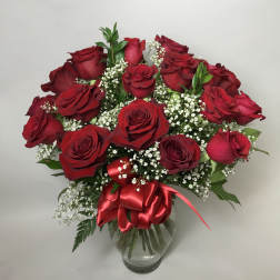 Bouquet of red roses with baby's breath in a clear glass vase and red ribbon