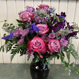 Pink roses and purple flowers arranged in a black vase