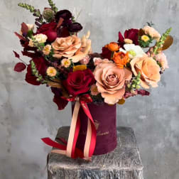 Bouquet of red and blush roses in a burgundy hat box with ribbon