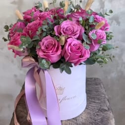Pink roses arranged in a white hat box with a ribbon
