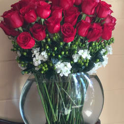 Bouquet of red roses and white flowers in a round glass vase