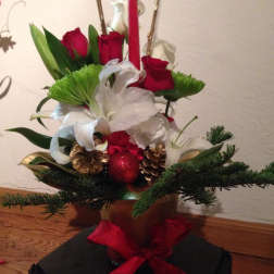 Red roses and white lilies in a holiday arrangement with pinecones and a red candle.