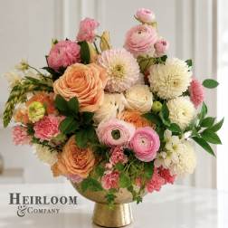 Pink, peach, and white flowers arranged in a gold pedestal vase