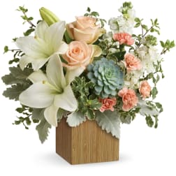 White lilies, peach roses, and pink carnations in a wooden cube vase