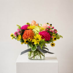 Mixed bouquet in a glass vase with pink, yellow, orange, and peach flowers