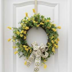 Yellow floral wreath with a patterned ribbon bow on a white door