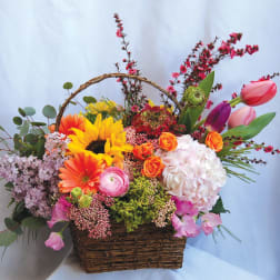 Colorful mixed flower basket with sunflowers, roses, tulips, and hydrangea