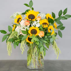 Sunflower and peach rose arrangement in a clear glass vase