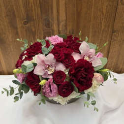 Bouquet of red roses and pink orchids in a low vase