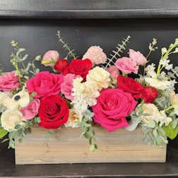 Pink and red roses arranged in a wooden box with white flowers