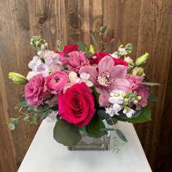 Pink and white bouquet with roses and orchids in a square glass vase