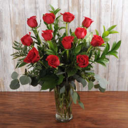 Tall bouquet of long-stemmed red roses arranged in a clear glass vase