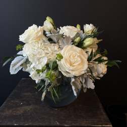 White roses and hydrangeas arranged in a dark vase