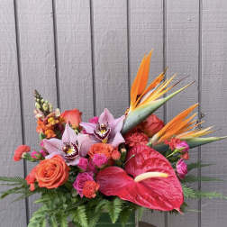 Tropical bouquet with orchids, roses, anthurium, and bird of paradise in a glass vase