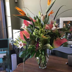 Tall tropical bouquet with lilies and bird-of-paradise in a glass vase